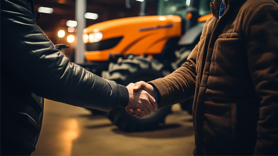 Two people shaking hands at tractor dealership
