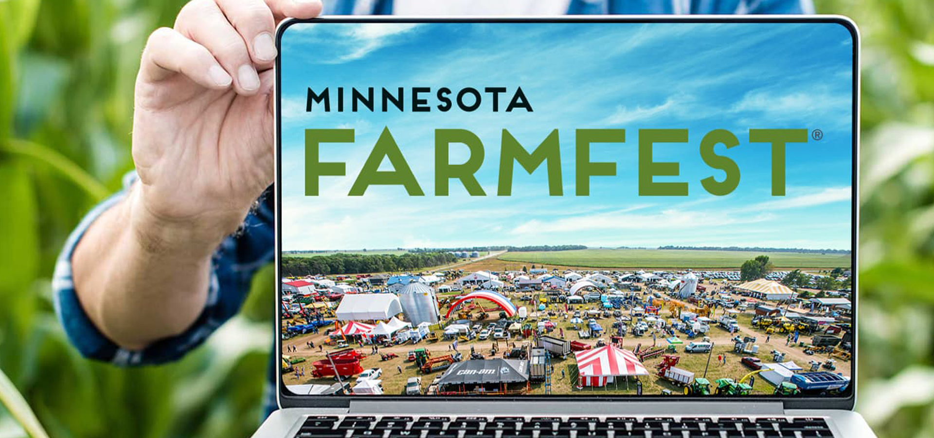 A farmer holding an open laptop with Farmfest logo